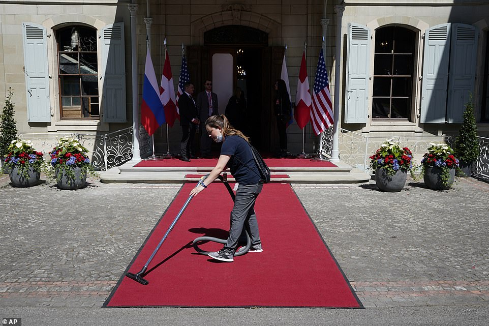 A cleaner hoovers the red carpet ahead of the arrival of Biden and Putin at the Villa de La Grange overlooking Lake Geneva